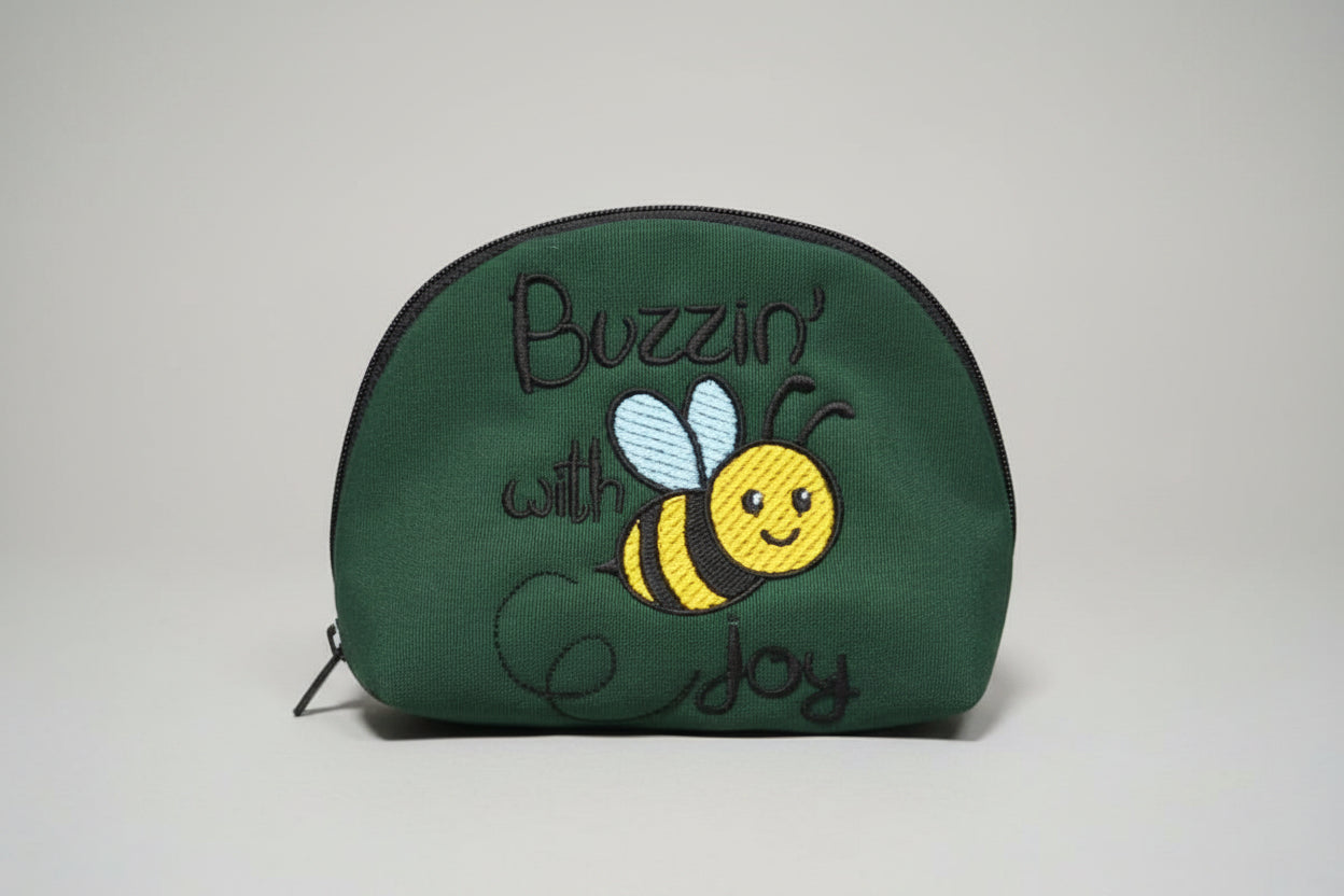 Green pouch with bee design and text on a cutting mat