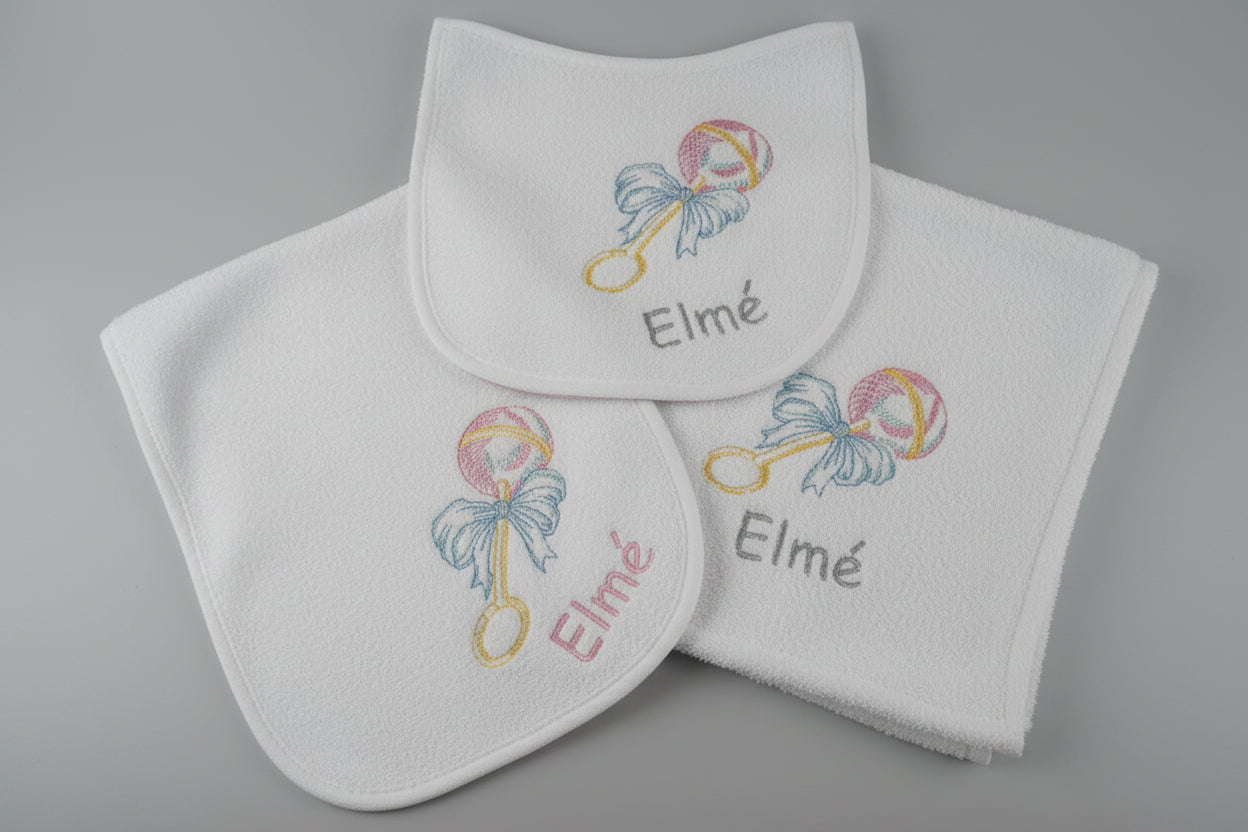 Baby bib and towel set with 'Elmé' embroidery on a textured surface