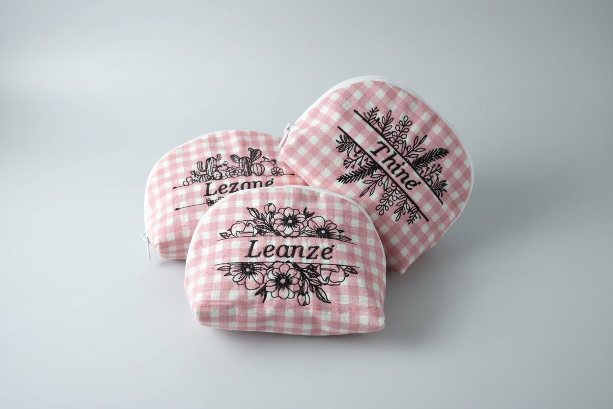Pink checkered pouches with floral and text designs on a round surface.