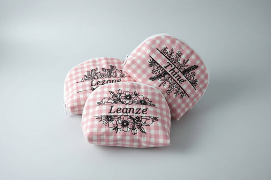 Pink checkered pouches with floral and text designs on a round surface.