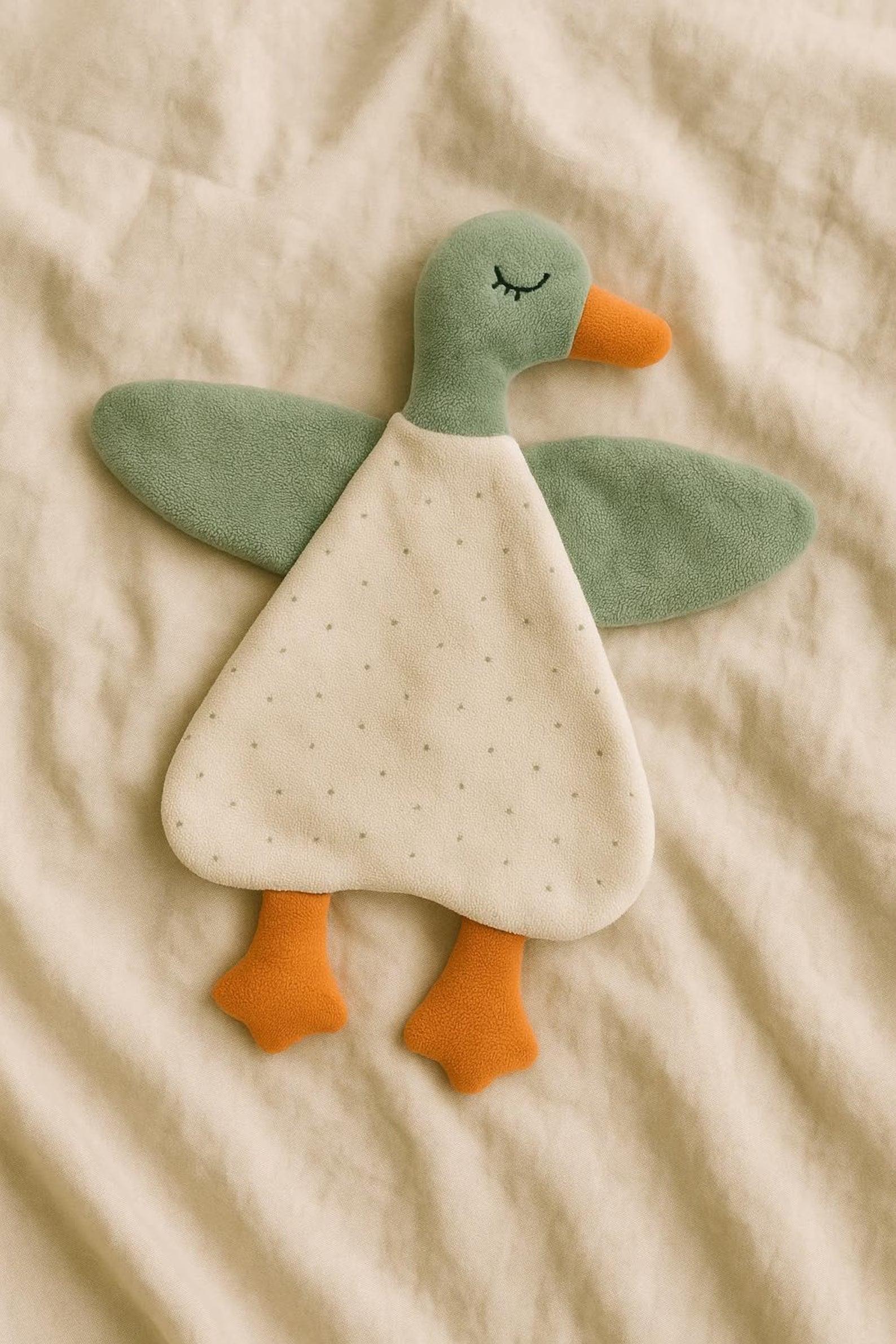 Plush toy duck on a beige fabric background